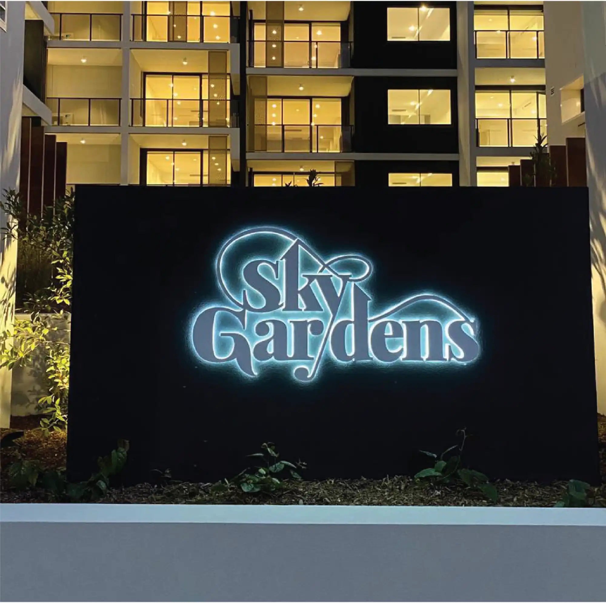 Illuminated ’Sky Gardens’ sign at the entrance of an apartment building.