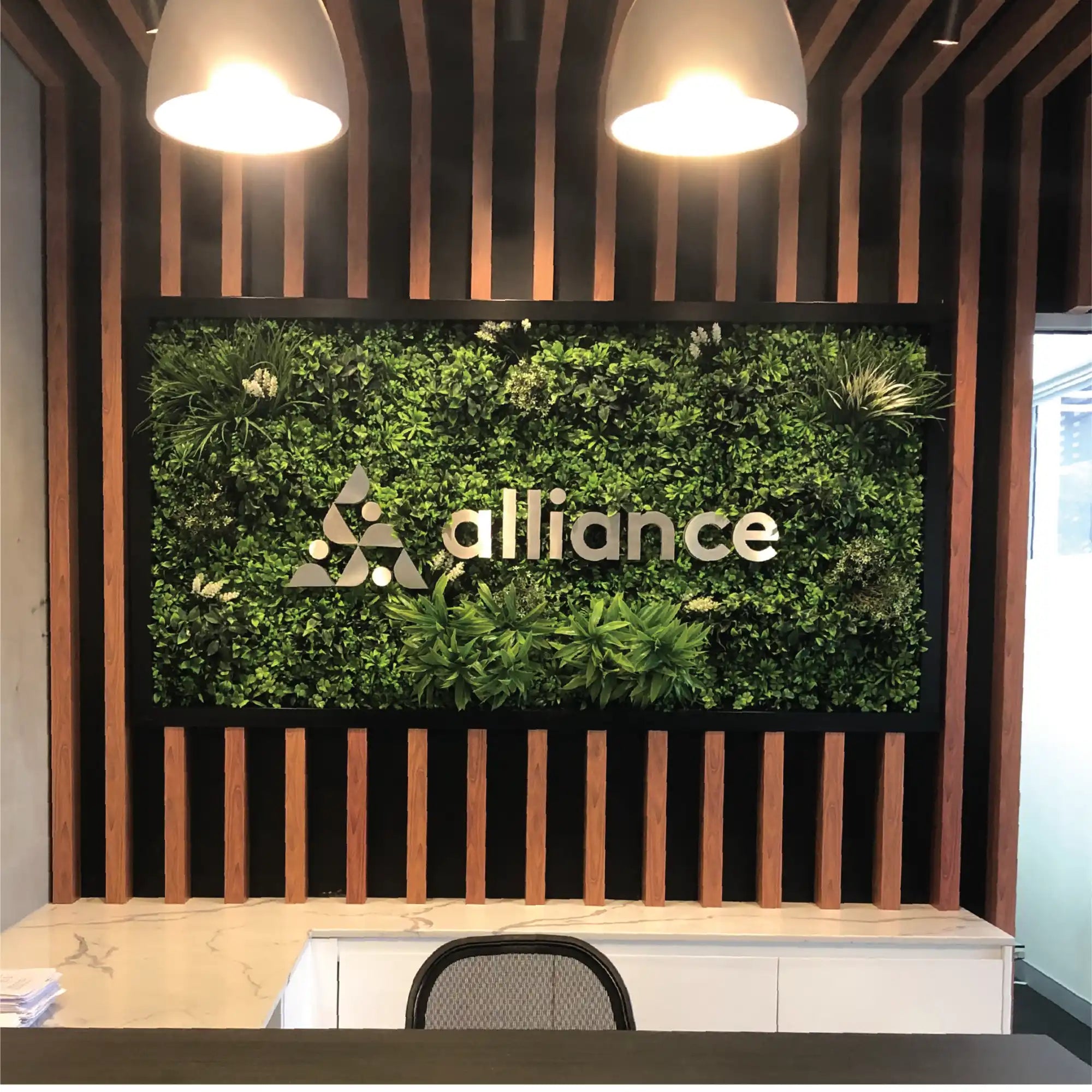 Reception desk with a vibrant green wall featuring a company logo.