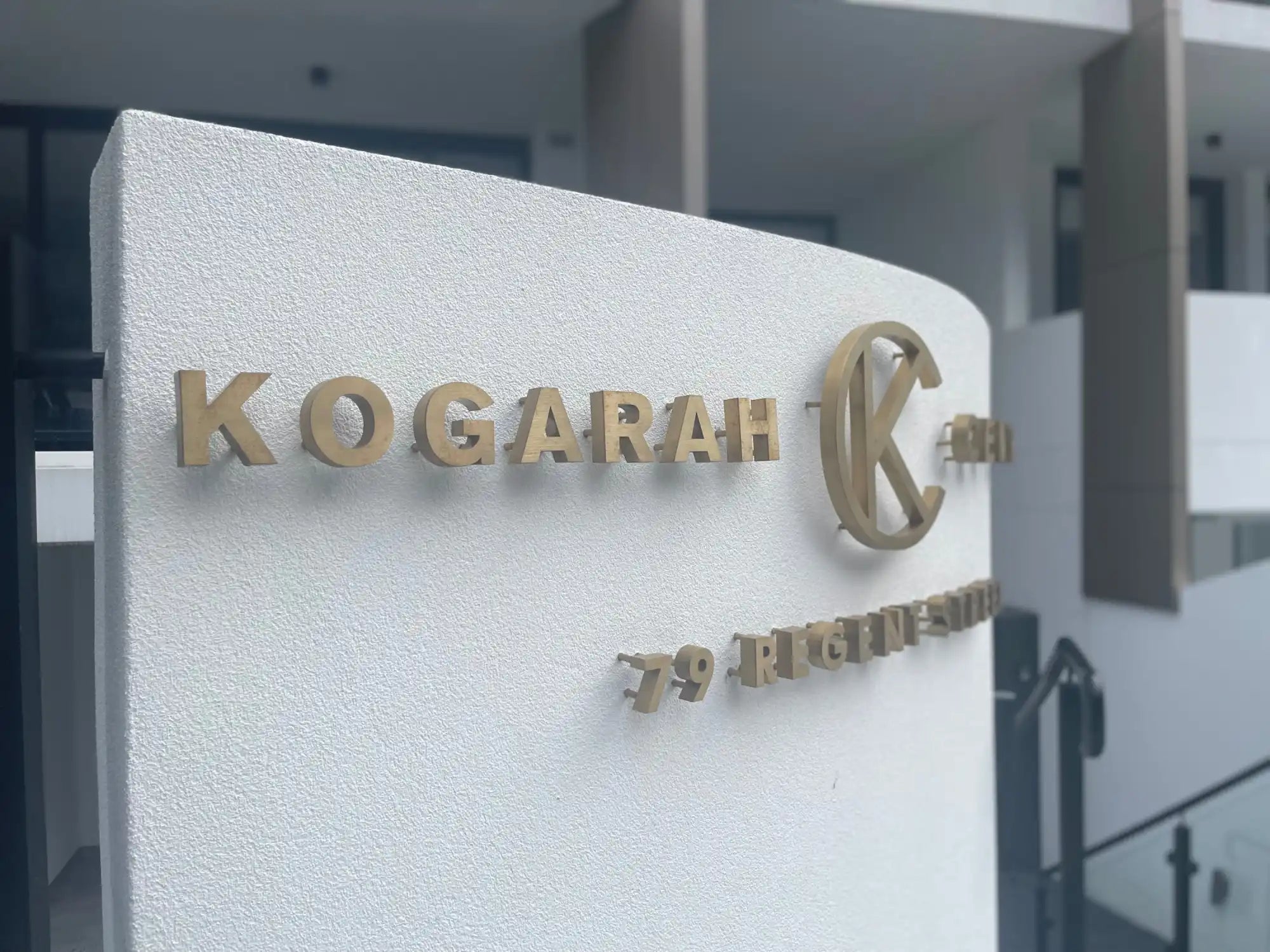 White outdoor sign with gold dimensional lettering.